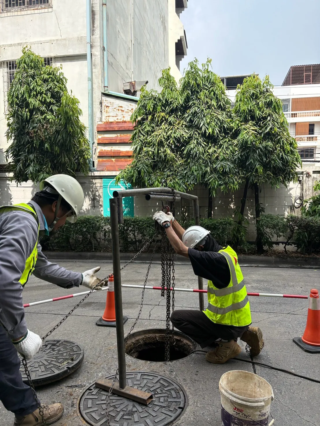 ทีมช่างทำงานที่บ่อพัก มีขาหยั่งและกรวยกั้นพื้นที่
